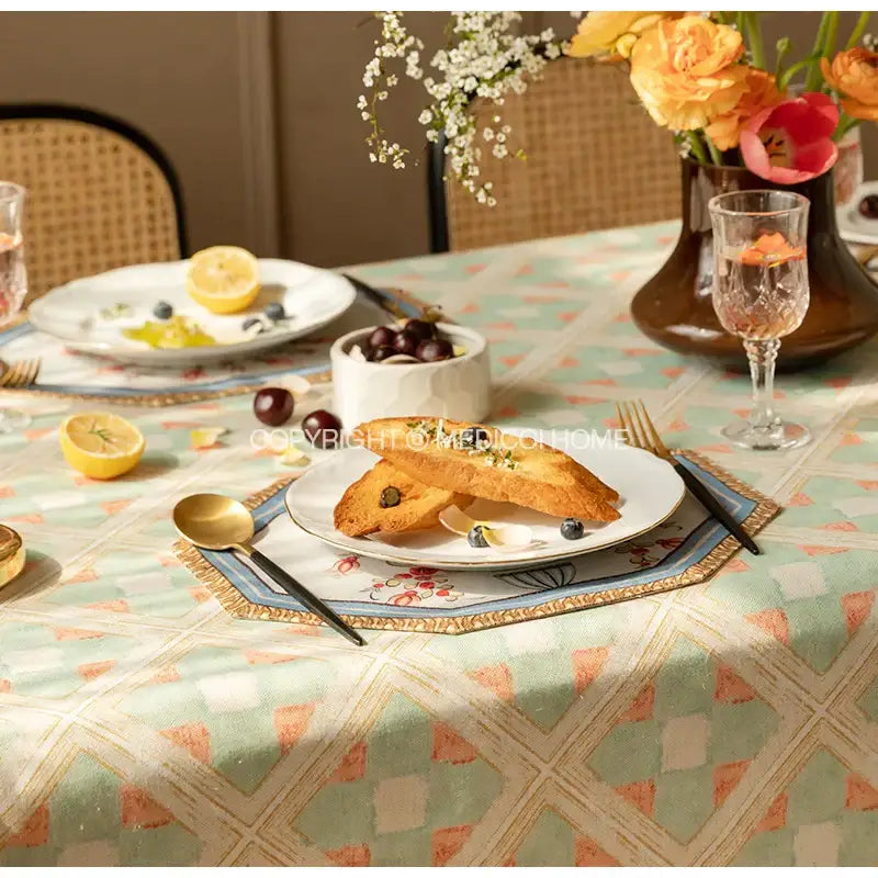 A white ceramic plate with gold-trimmed edges holding toasted bread and blueberries on decorbites baroque flowers fringe placemat set