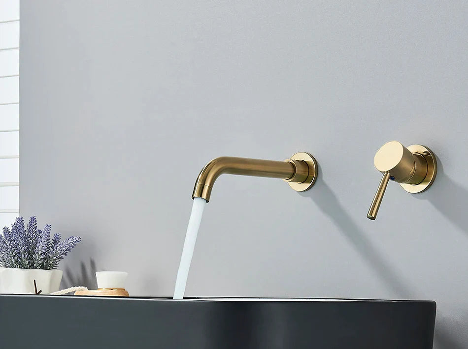 Modern gold-toned basin faucet wall mounted bathroom fixture with brushed brass finish and hot water control flowing stream