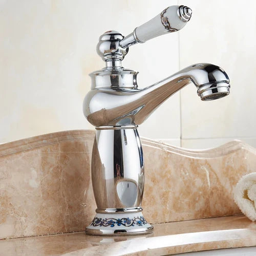 Bathroom faucet with bronze finish chrome body, white ceramic handle with blue floral detailing, and ornate base