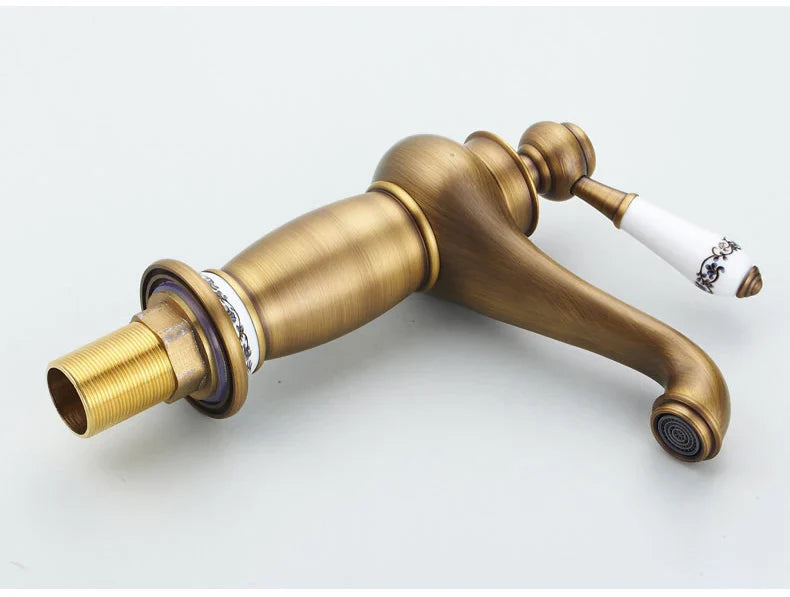 Antique bronze finish bathroom faucet with single brass handle and white ceramic handle featuring black floral detailing