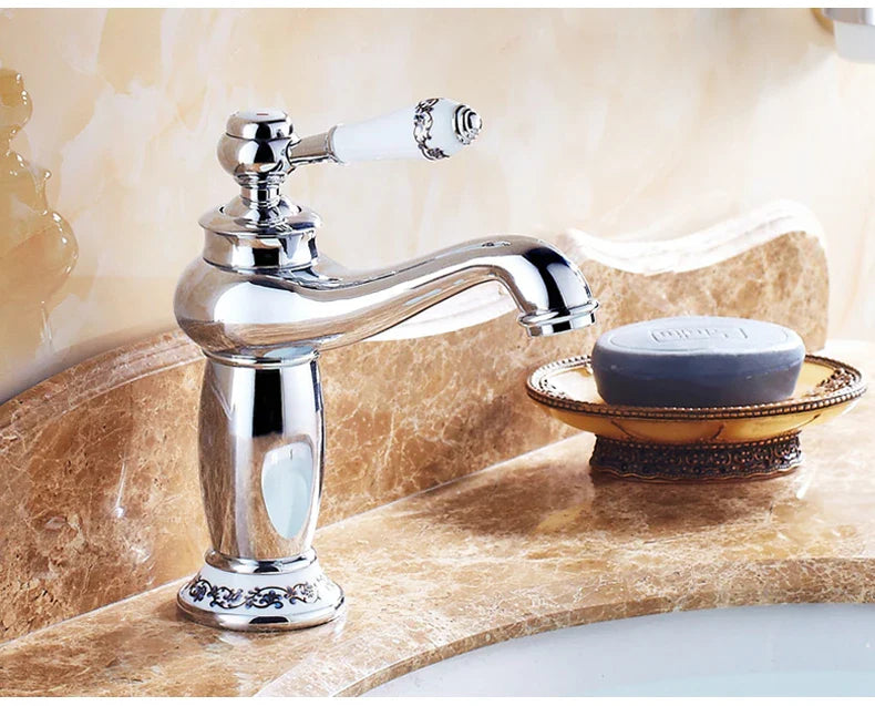 Chrome-finished bathroom faucet with white ceramic handle and ornate detailing in an antique bronze finish