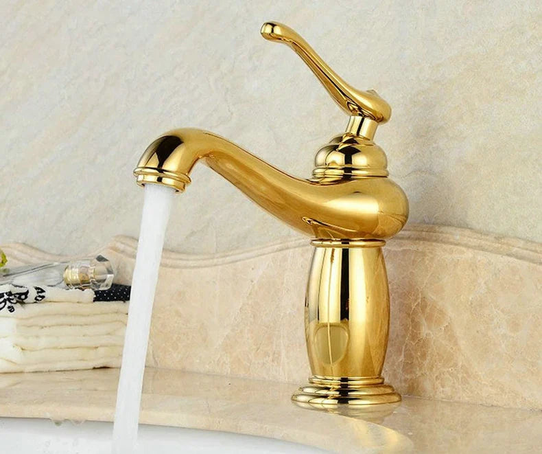 Golden brass-finished single-handle bathroom faucet with curved spout and ornate vintage-inspired design in bronze finish