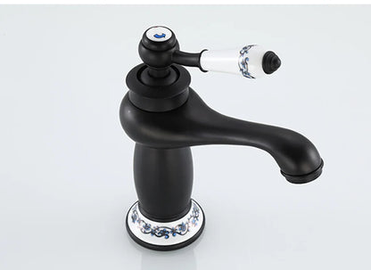 Bathroom faucet with bronze finish featuring black matte body and white ceramic handle with blue floral patterns