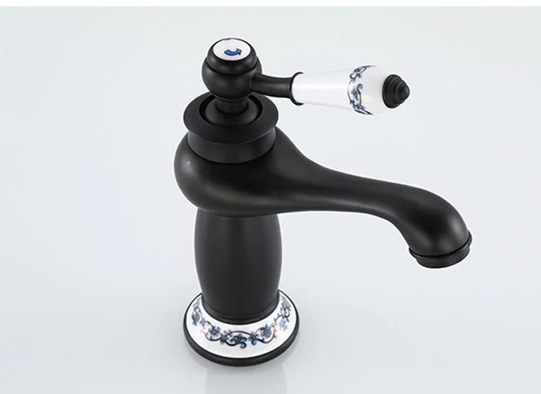 Bathroom faucet with bronze finish featuring black matte body and white ceramic handle with blue floral patterns