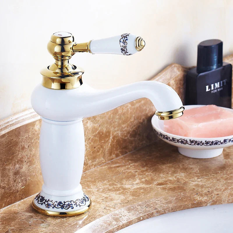 White ceramic bathroom faucet with bronze finish gold accents and ornate blue floral detailing on handle base and spout