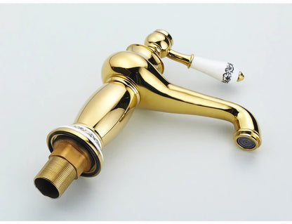 Gold-finished bathroom faucet with white ceramic handle and black floral detailing in antique bronze finish