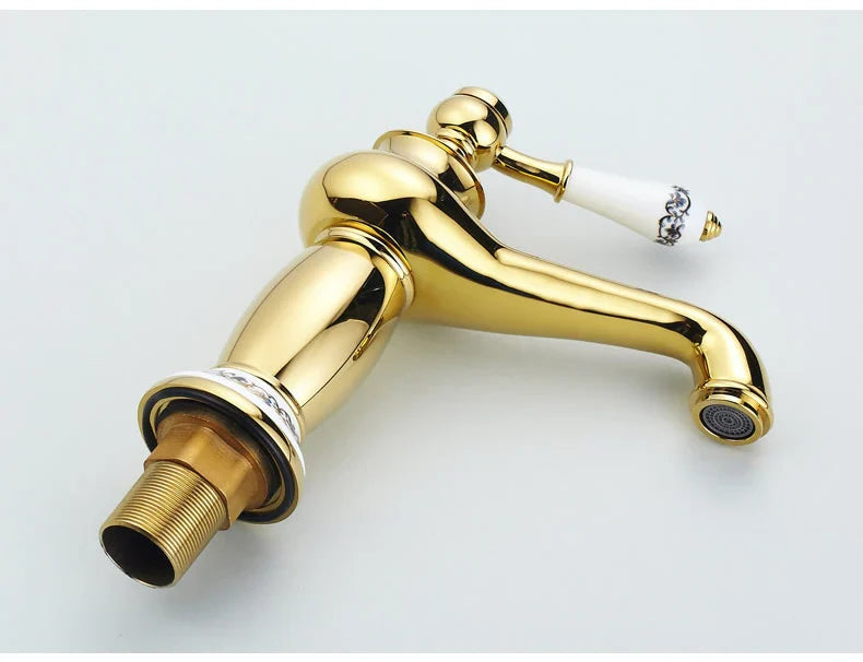 Gold-finished bathroom faucet with white ceramic handle and black floral detailing in antique bronze finish