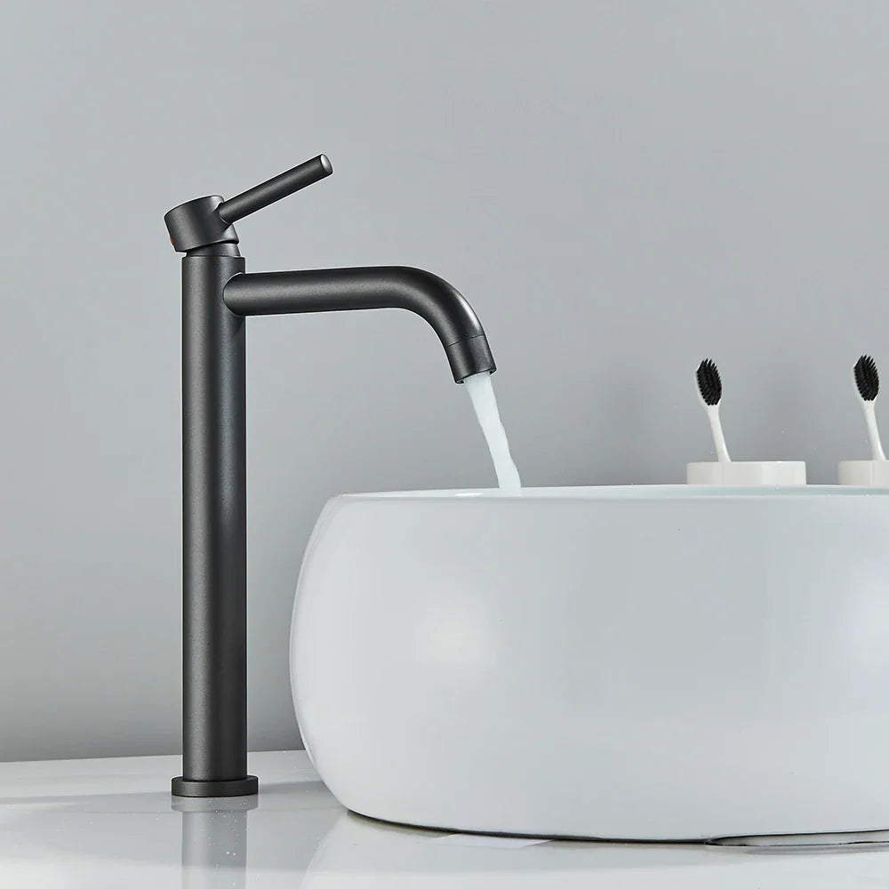 Black matte bathroom faucet with a sleek, tall design and curved spout in brushed gold mixer tap style