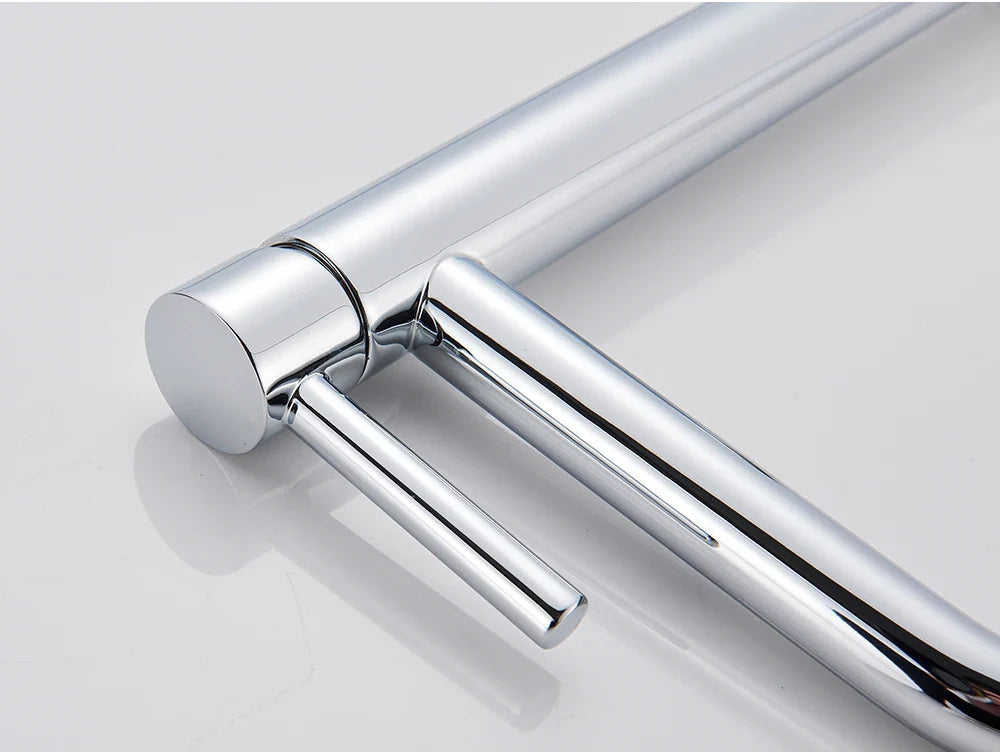 Chrome-finished metal towel rack with sleek cylindrical bars and polished surface displayed alongside bathroom faucet brushed gold mixer tap