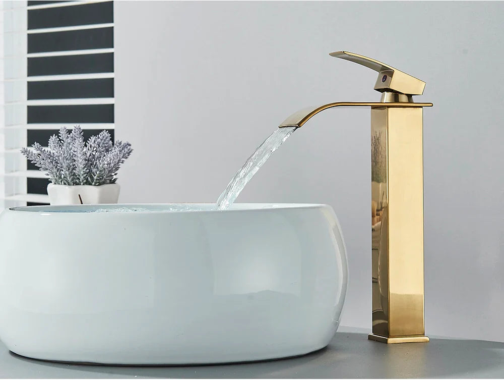 Gold-toned brass bathroom sink faucet with waterfall spout stainless steel deck mount and sleek modern design