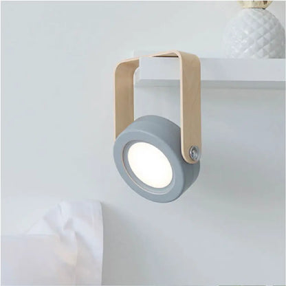 Gray circular battery-operated wall sconce lantern with light wood handle for versatile indoor lighting