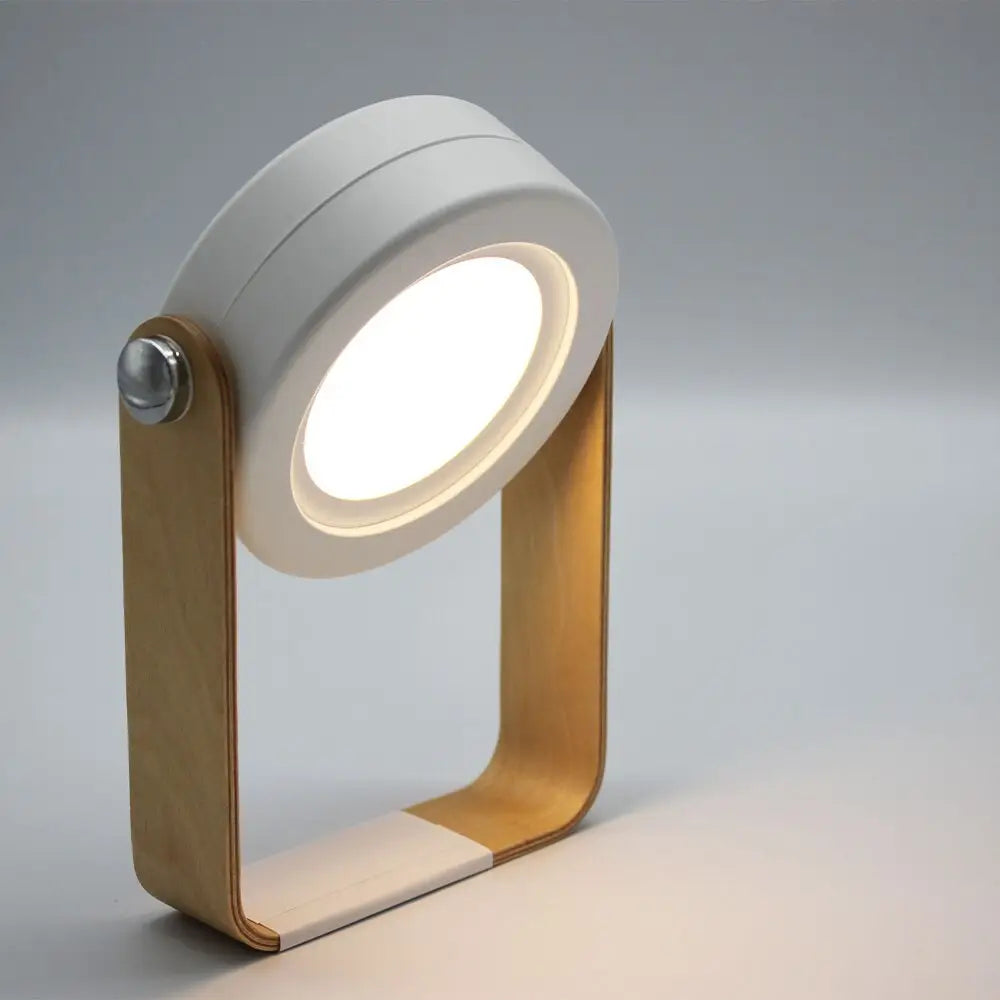A battery-operated wall sconce lantern with a sleek white circular head and gold-toned wooden frame