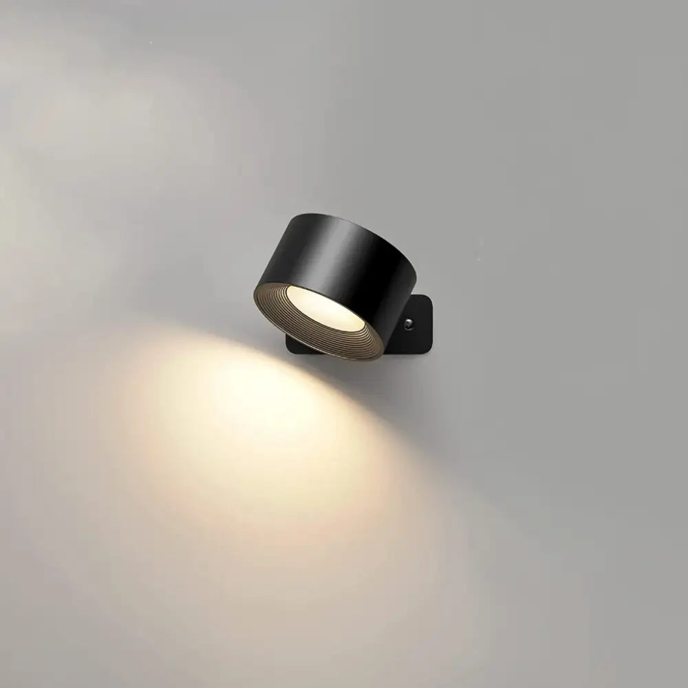 Black cylindrical battery operated wall sconce with textured ribbed interior and warm white illumination, remote controlled
