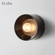 A sleek black bauhaus metal wall lamp with a warm glowing bulb ideal for living room led sconce lighting