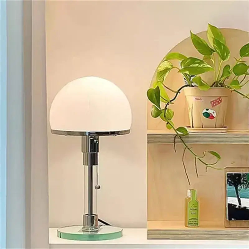 A bauhaus chrome and milk white glass table lamp with a frosted white glass shade and polished chrome stem for bedroom lighting