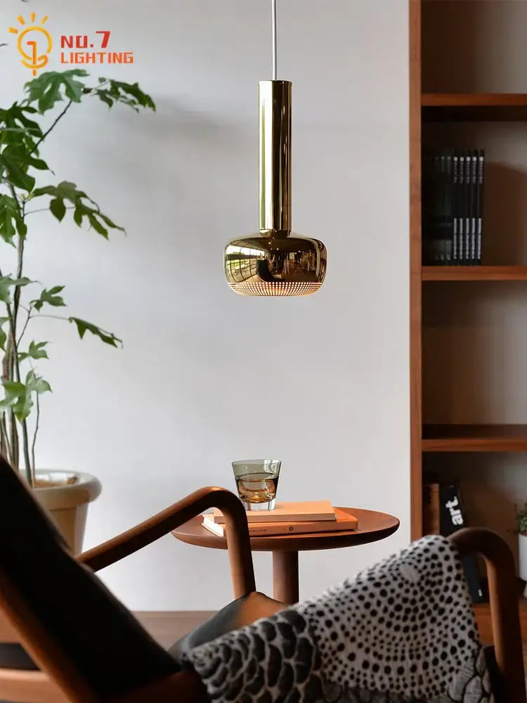 A sleek modern bauhaus copper chrome pendant light with polished brass finish and cylindrical design for kitchen island