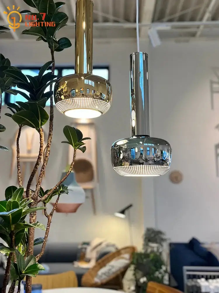 Two bauhaus copper chrome pendant lights with gold and chrome finishes feature spherical glass shades with led bulbs