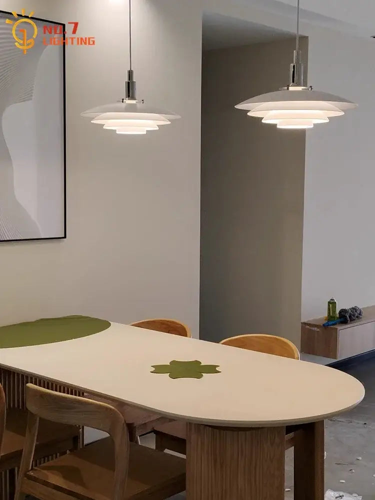 Modern white bauhaus flying saucer pendant light with layered disc-shaped shades and sleek metallic fixtures above dining table