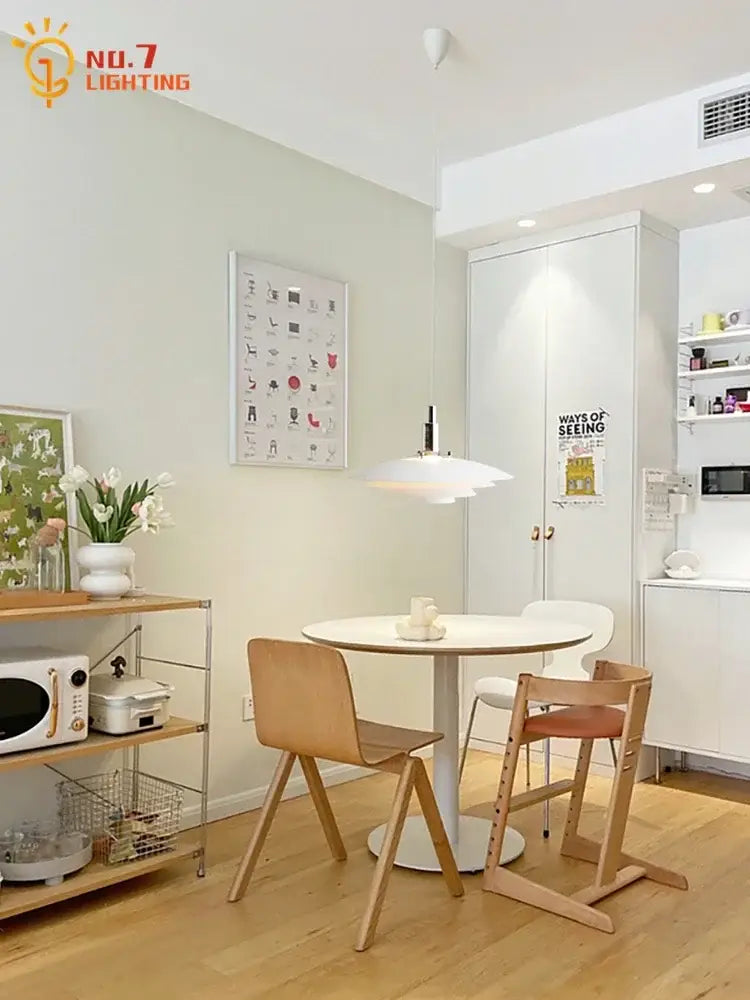 White round dining table with sleek pedestal base paired with black bauhaus flying saucer pendant light in dining room