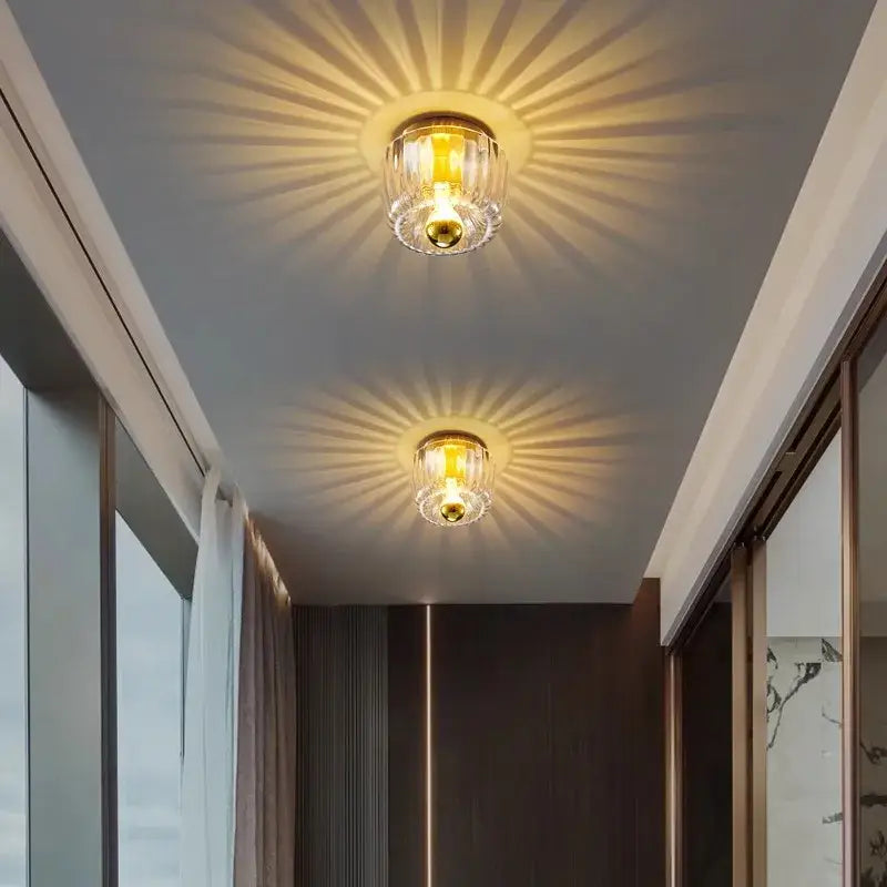 Two golden-finished bauhaus glass e14 wall lamps with clear ribbed glass shades emitting warm sunburst light patterns
