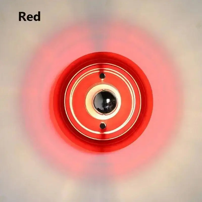 Red circular camera lens with gold-toned rings and black center featured in bauhaus green and clear glass led wall sconces decorbites led wall