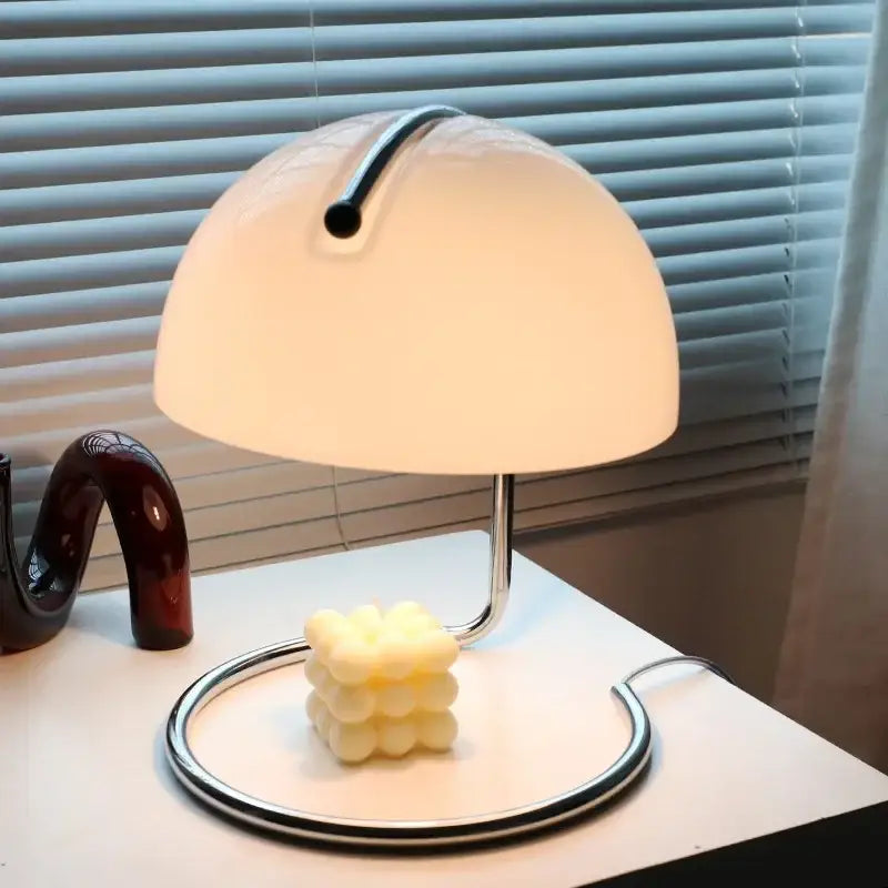 A bauhaus mushroom modern led desk lamp with a translucent white acrylic shade and polished chrome base for bedroom use