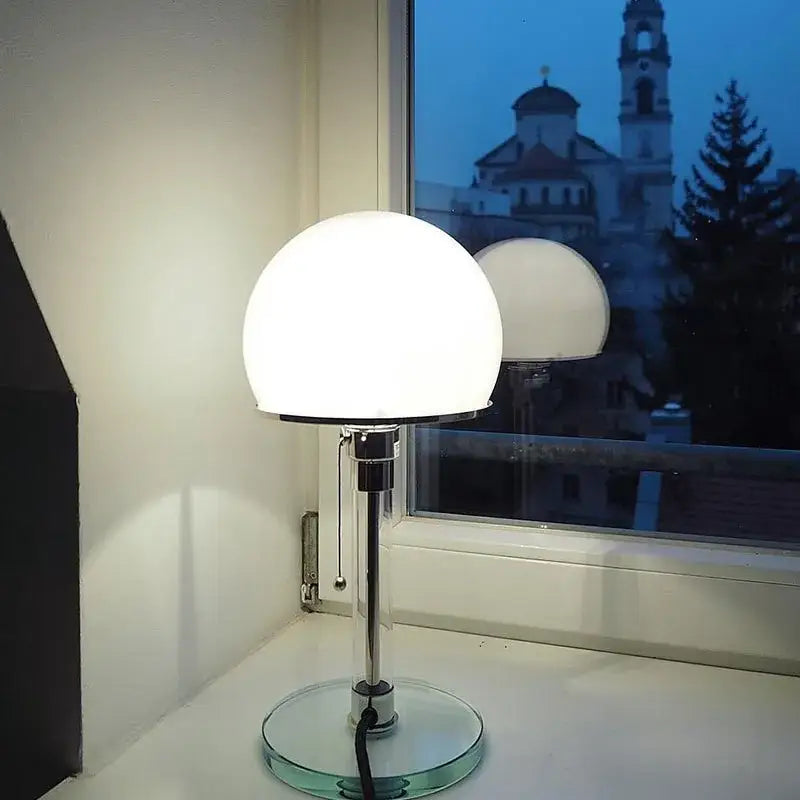 A bauhaus mushroom table lamp with frosted white glass shade and chrome metal base for bedroom use