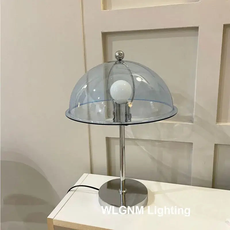 A bauhaus mushroom table lamp with chrome finish and transparent blue dome for bedroom night light
