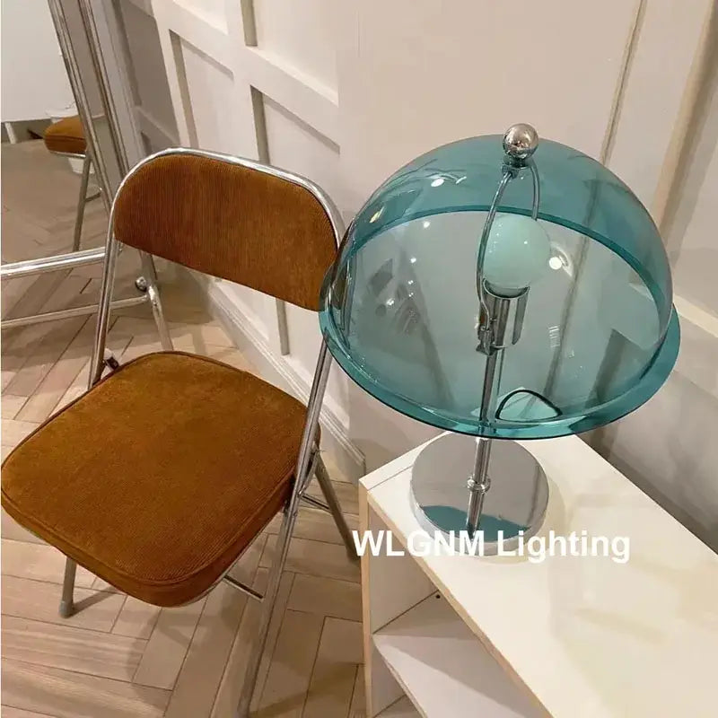 A bauhaus mushroom table lamp with a translucent teal glass dome and polished chrome base for bedroom night light
