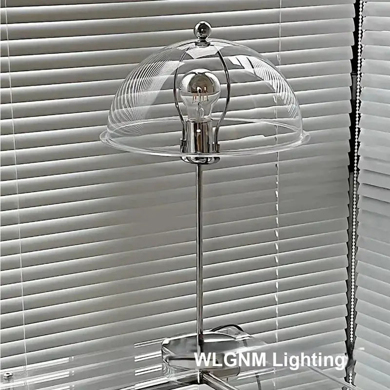 A sleek chrome bauhaus mushroom table lamp with clear glass dome and exposed bulb for bedroom night light