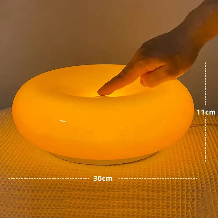A warm glowing orange bauhaus decorbites donut wall lamp with a smooth modern design for bedroom atmosphere lighting