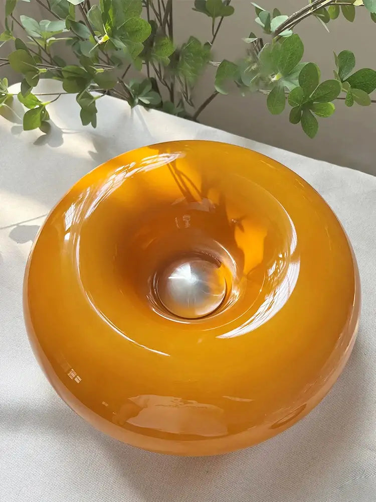 Glossy amber glass wall lamp with a metallic sphere center in Bauhaus orange decorbites donut wall lamp design