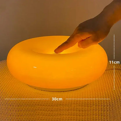 A bauhaus orange glass style glass table lamp with smooth rounded edges and warm orange light for bedroom use