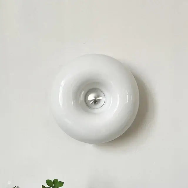 White glossy ceramic wall sconce with metallic accent complementing bauhaus orange glass table lamp for bedroom use