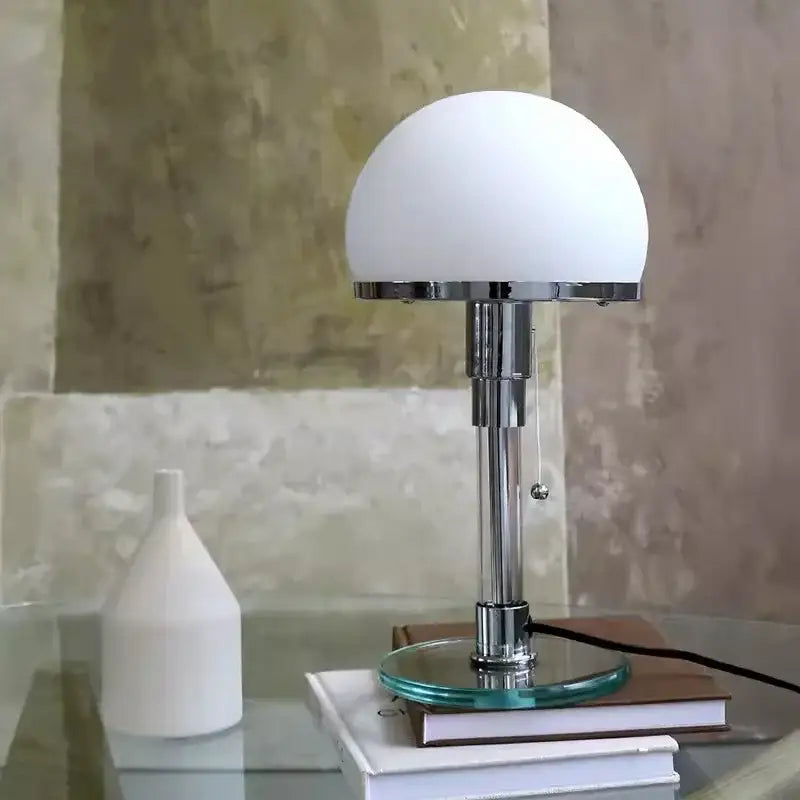 A bauhaus glass ball desk lamp with chrome finish, frosted white globe, and green-tinted teal glass base for bedroom use