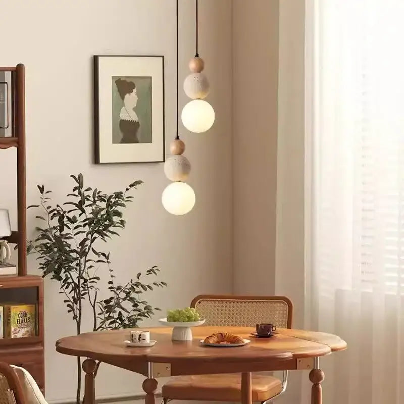 A modern bauhaus pendant light with travertine stone and wood spheres in matte white works beautifully in dining rooms