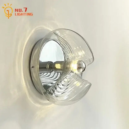 Clear sculpted bauhaus wavy glass wall lamp with chrome base and filament bulb for bedroom lighting
