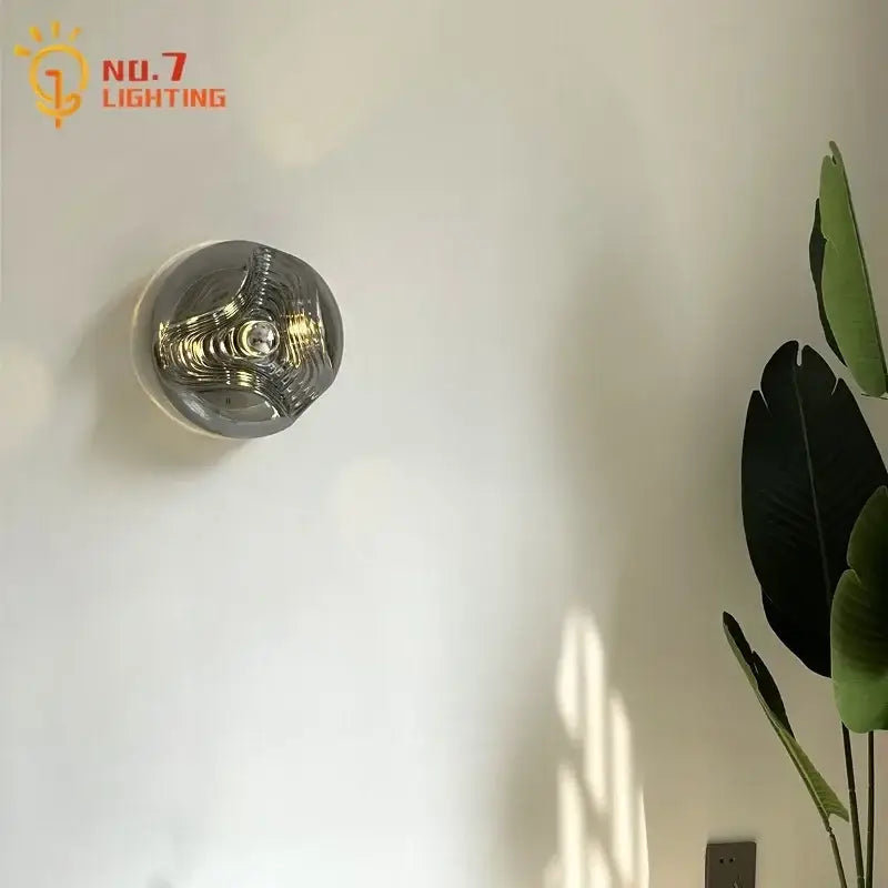 A sleek bauhaus wavy glass wall lamp with clear glass dome and metallic interior for bedroom lighting