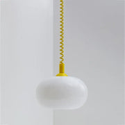 A bauhaus glass pendant light with sleek white opal glass and vibrant yellow coiled cord for dining room lighting