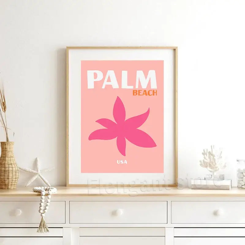 A framed DecorBites™ beach travel poster with pink background and stylized magenta flower for living room decor
