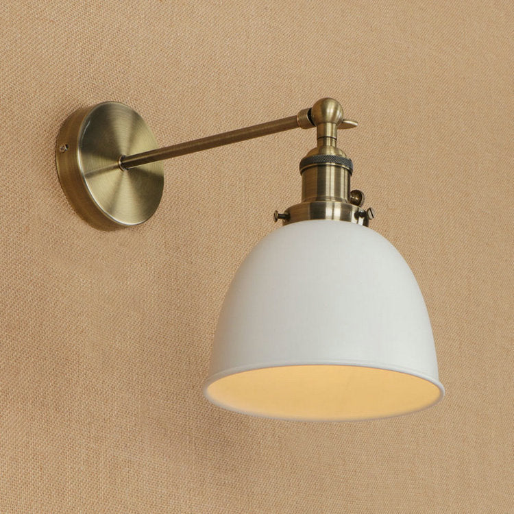 White dome-shaped wall sconce with brass accents and adjustable arm designed for bedroom lights