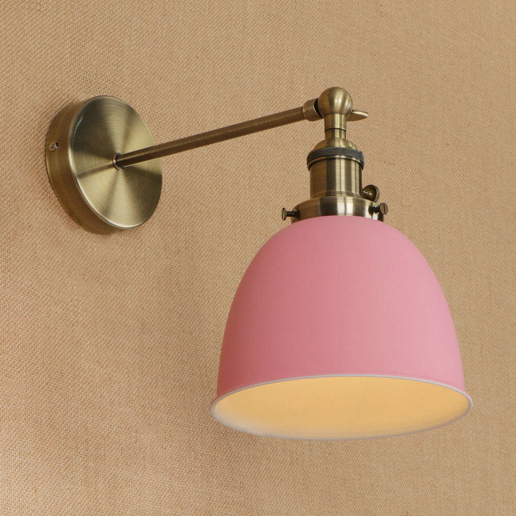 Pink dome-shaped bedroom wall sconce with brass accents and adjustable arm for versatile lighting use