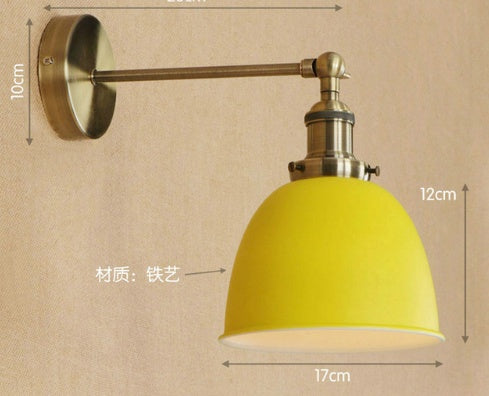 Yellow dome-shaped wall lamp with brass accents and adjustable arm.