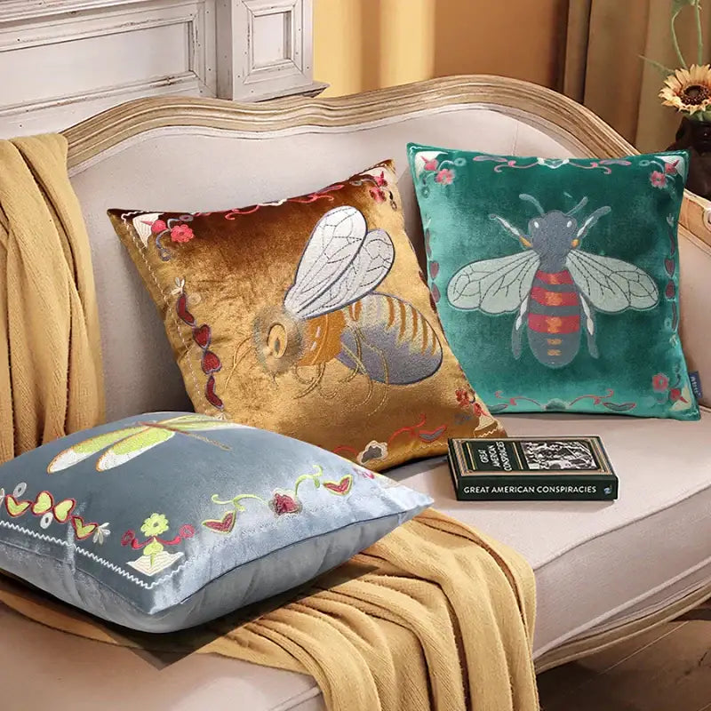 Three decorative velvet cushion covers with bee embroidery in yellow green and blue for living room decor