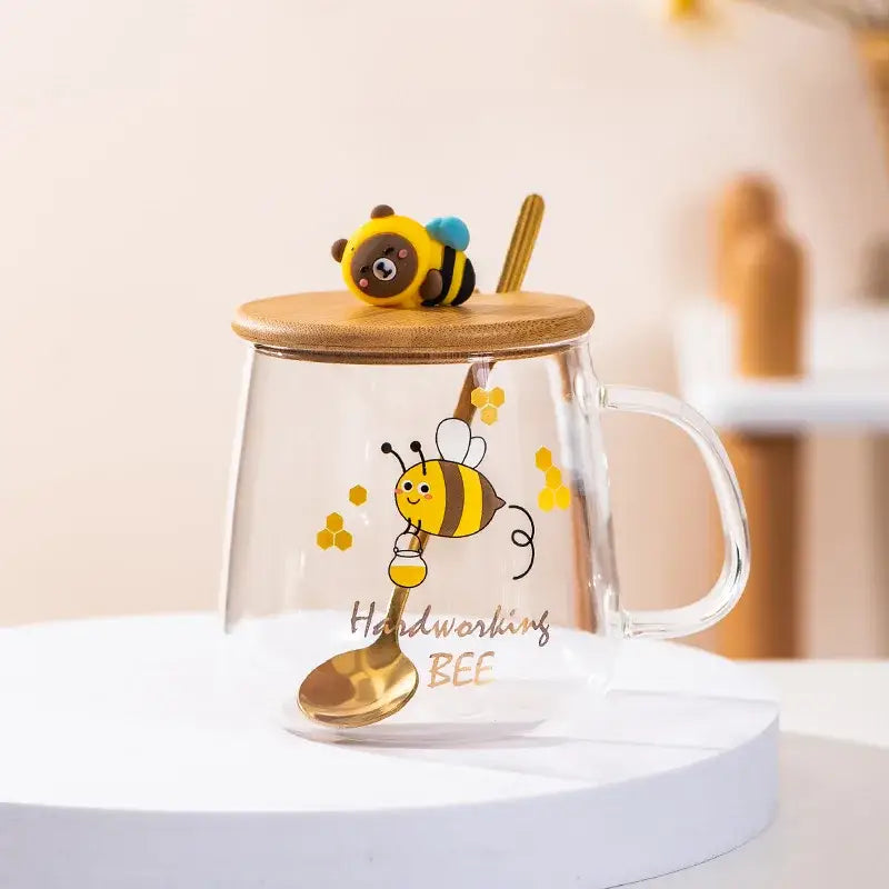 Clear glass bee glass spoon milk cup with bamboo lid featuring cartoon bee design and a golden spoon for kitchen use