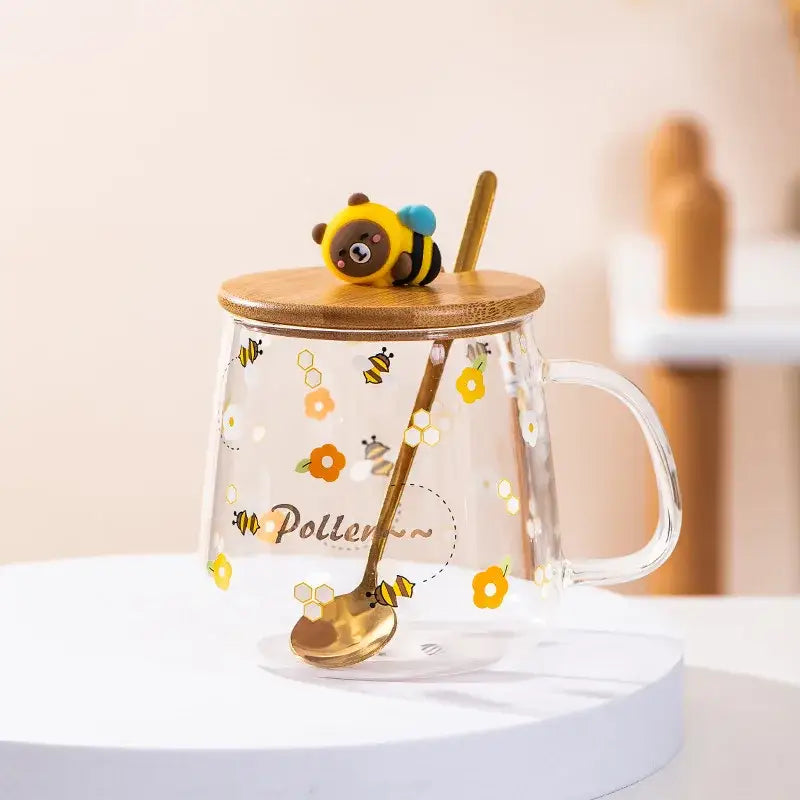 Clear glass spoon milk cup with bamboo lid and gold spoon featuring yellow bee and flower decals for kitchen use