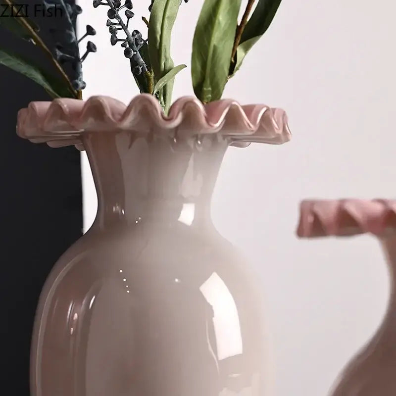 A blush pink ceramic vase with scalloped pink flower edge holding greenery for living room decor
