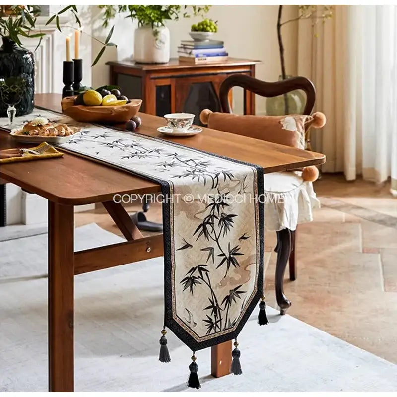 Beige table runner with black bamboo leaf swallow print embroidery and tassels for dining room decor by decorbites