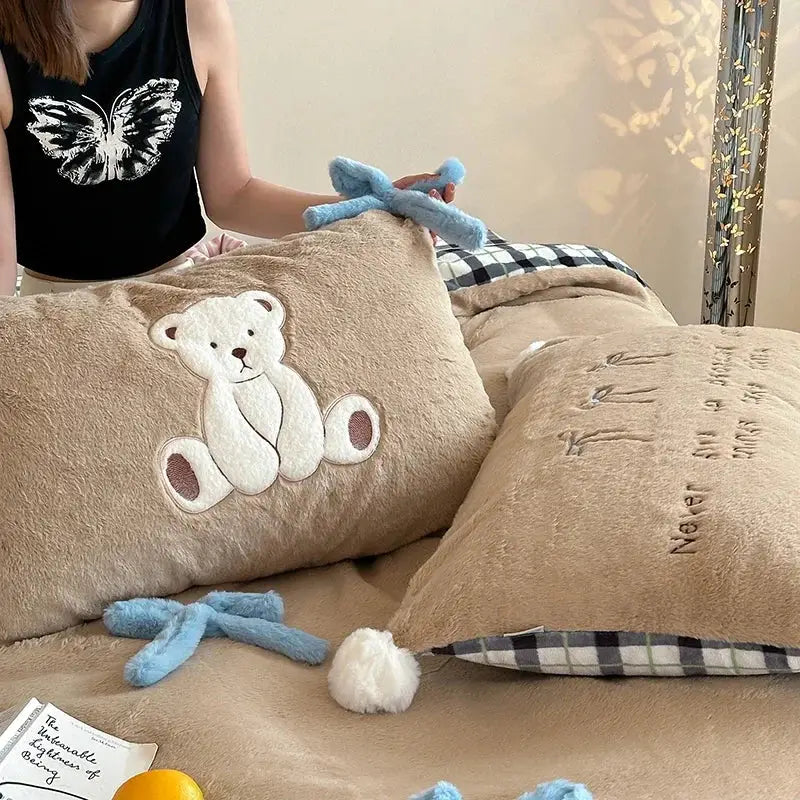 Beige plush pillow with white embroidered teddy bear on velvet duvet bedding set in beige and blue bedroom decor