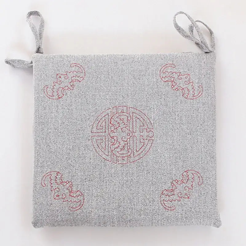 Gray woven linen seat cushion with red embroidered dragon motifs and fabric loops for hanging by decorbites
